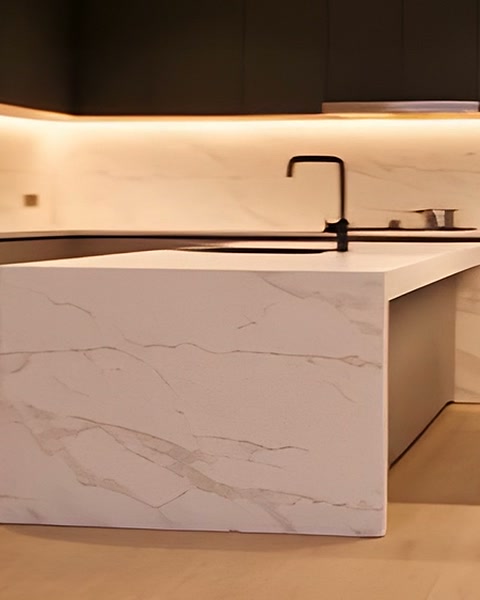 A white stone island with soft grey veining and a black tap.